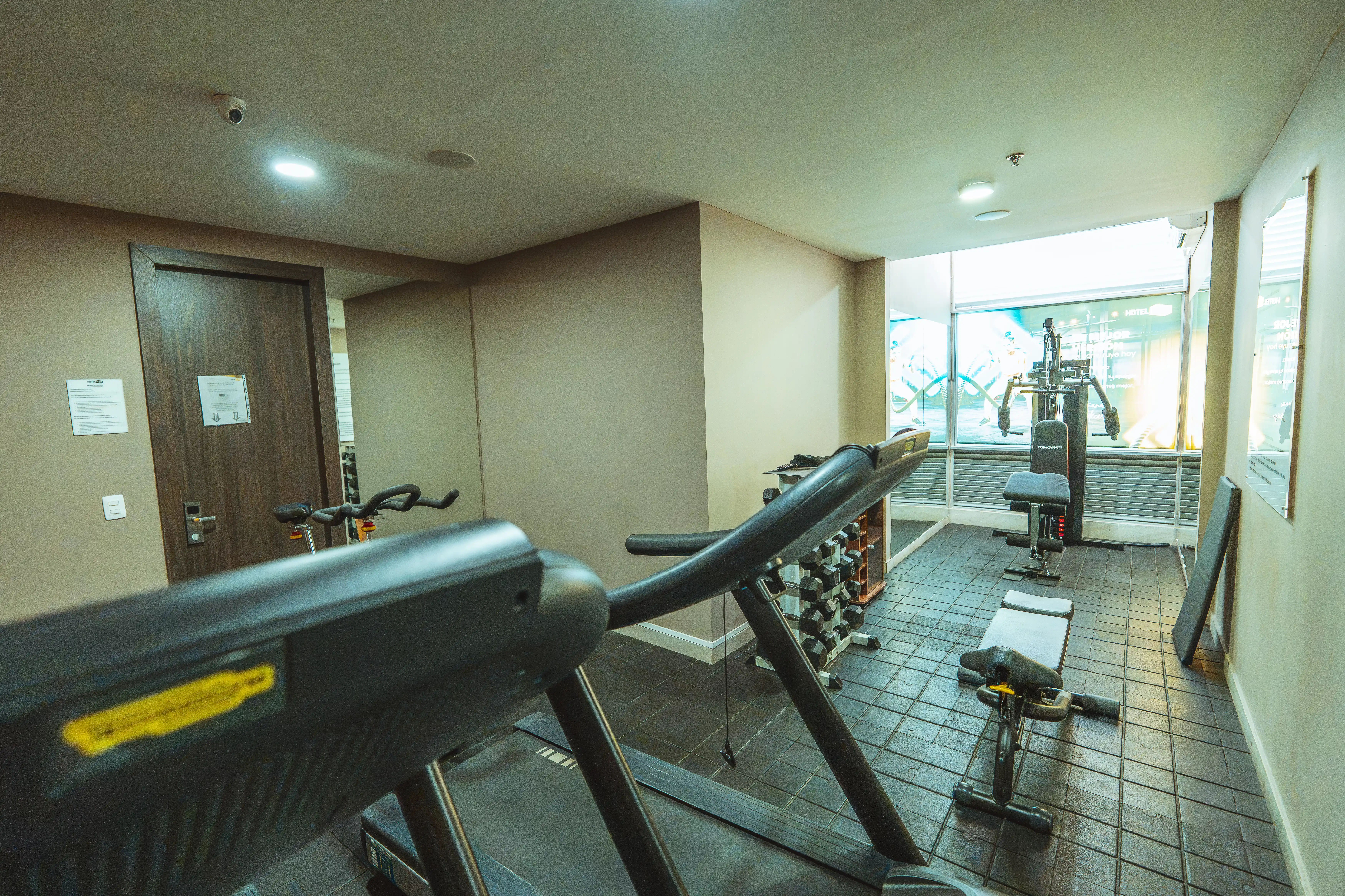 Gimnasio del Hotel F25 con máquinas y vista a la ciudad